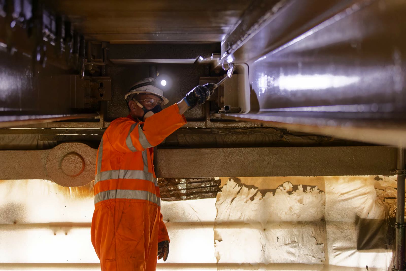 Worker restoring metalwork within the scaffolded access space beneath the bridge deck